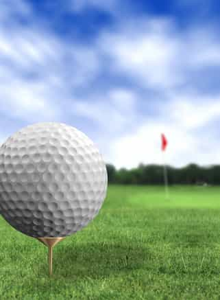 golf ball close up in a course with green grass and a blue sky